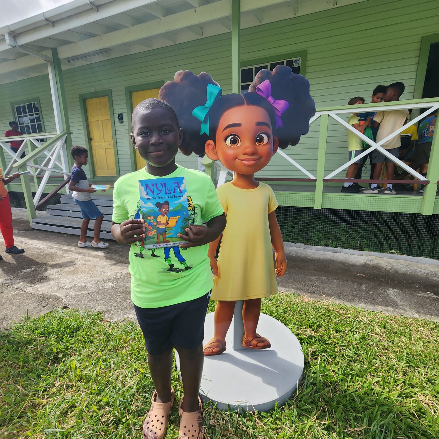 A young boy holding a Nyla book beside the life-size Nyla character cutout